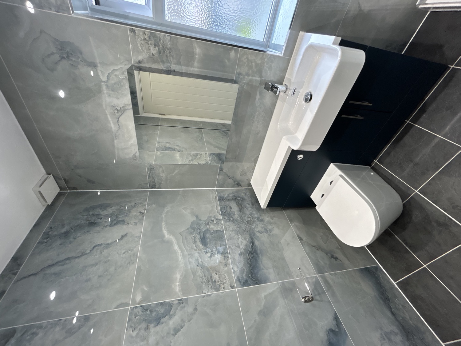 Completed grey marble-effect bathroom with a navy vanity unit and chrome fittings